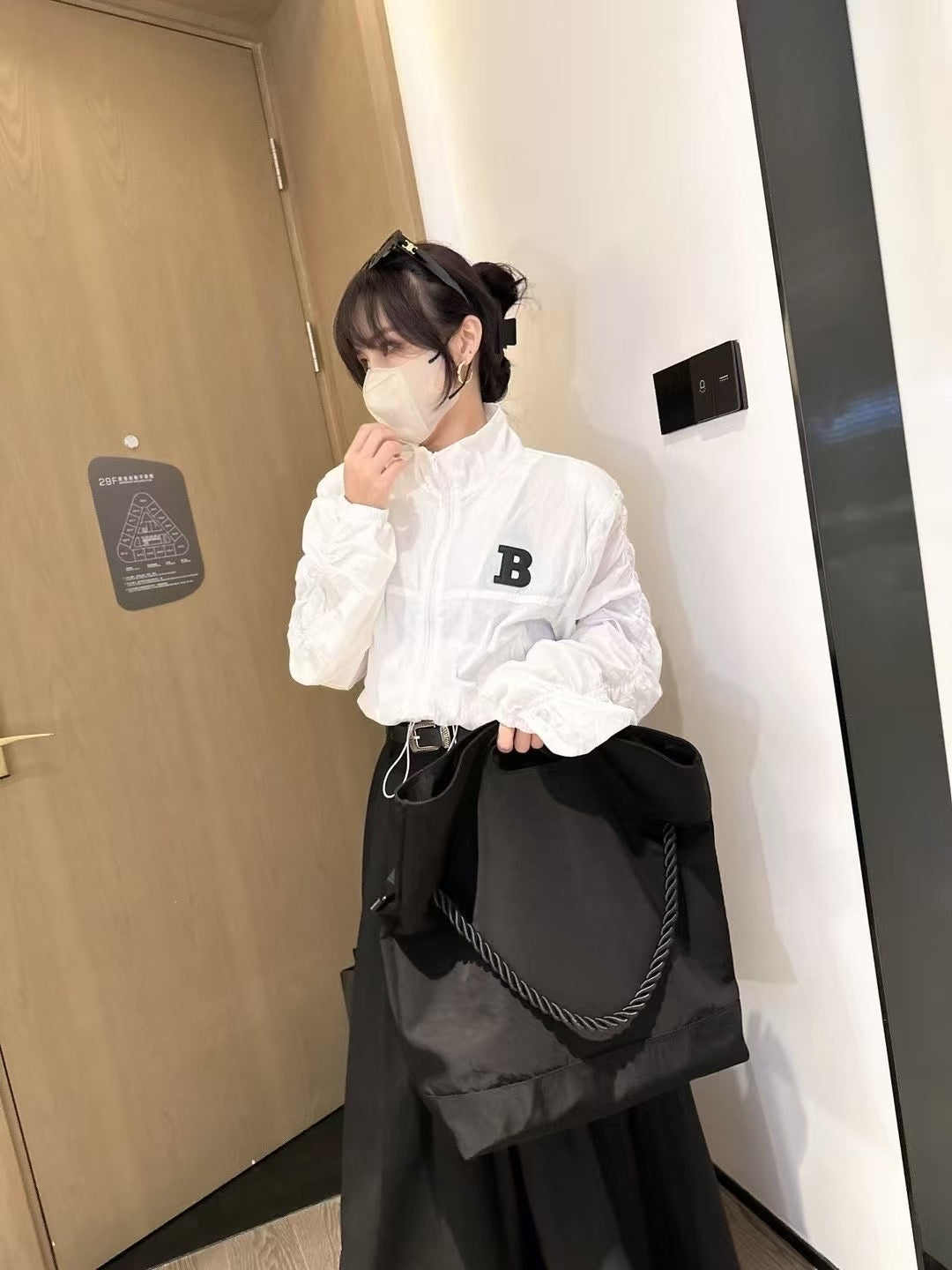 Person wearing a white shirt with a letter 'B' logo, holding a black bag indoors.Black handbag with a rope handle held by a person on a white surface.,High-quality red tote bag for women and girls from a new Indian fashion brand. Features a unique top-fold flap design and sturdy braided black rope handles. Perfect for carrying laptops and essentials, making it a stylish and functional bag for office, college, or casual outings in India. A chic and trending design for the modern Indian woman, available onlin