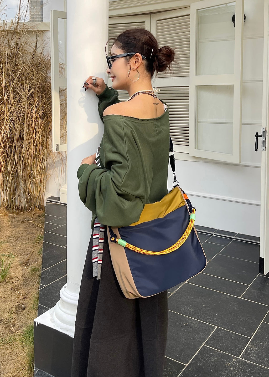 Woman standing outside a house holding a colorful bag Multi-pocket travel tote bag with 20-litre capacity and compact dimensions (35 x 35 x 10 cm), featuring a wide adjustable strap and color-blocked utility design. Lightweight, durable, and ideal for travel, college, or daily use. A high-performance everyday essential from Tales of Totes – built for comfort, style, and smart organization in India’s fast-paced lifestyle."
