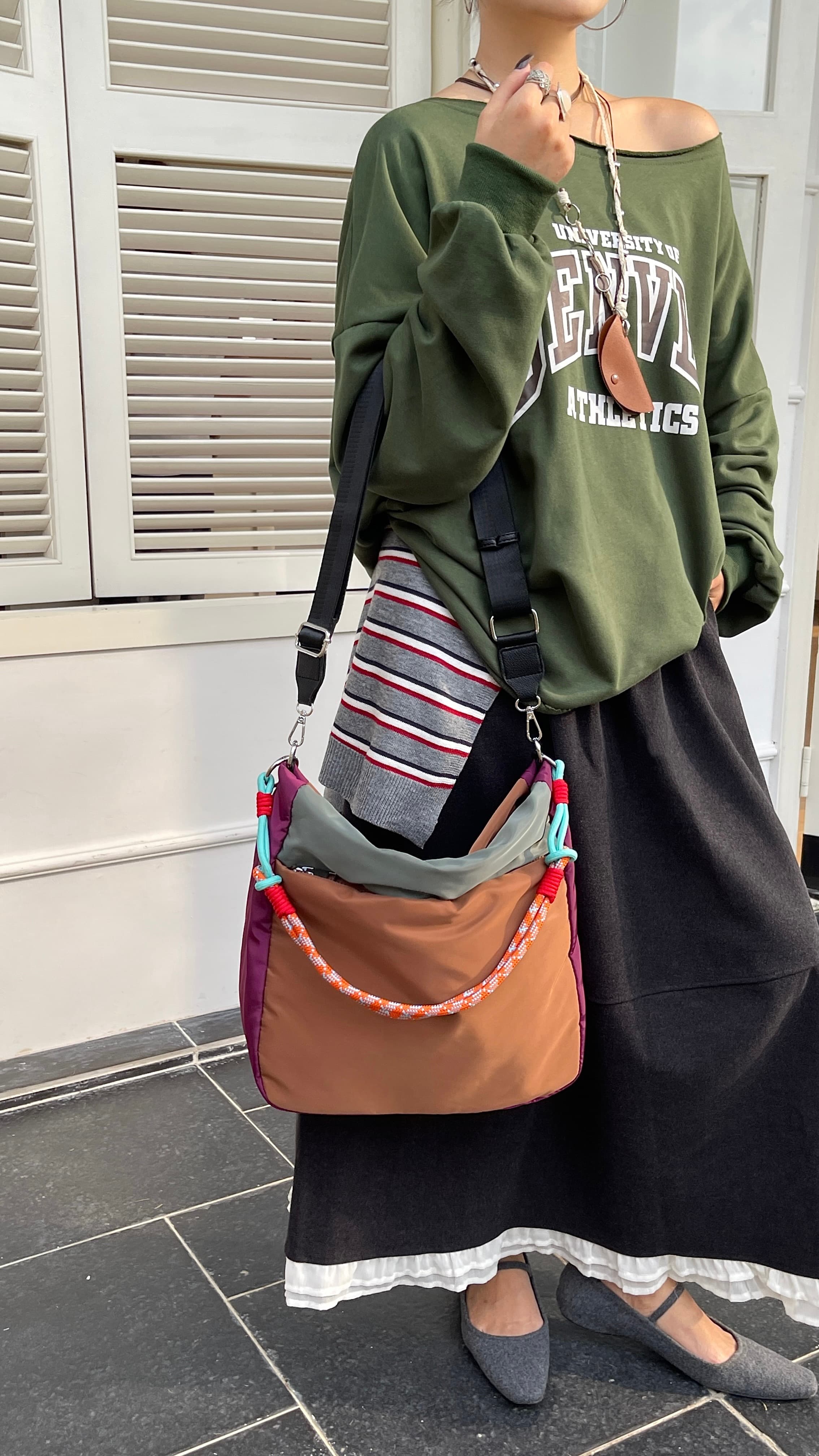 Person wearing a green sweatshirt and black skirt, holding a brown handbag with colorful accents. Multi-pocket travel tote bag with 20-litre capacity and compact dimensions (35 x 35 x 10 cm), featuring a wide adjustable strap and color-blocked utility design. Lightweight, durable, and ideal for travel, college, or daily use. A high-performance everyday essential from Tales of Totes – built for comfort, style, and smart organization in India’s fast-paced lifestyle."
