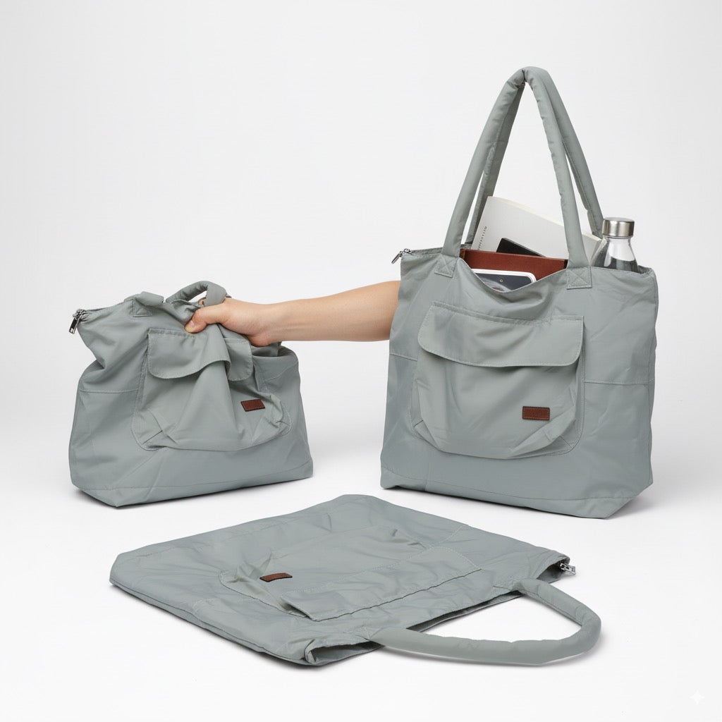 Gray tote bag with a hand reaching in to place a bottle, on a white backgroundLightweight nylon tote bag with a padded handle design and front flap pocket – perfect for everyday errands, gym, shopping, or casual travel. Spacious, foldable, and easy to carry with a functional structure that balances fashion and utility. A bold statement piece from Tales of Totes, designed for modern Indian lifestyles and a stylish alternative to basic canvas totes."
