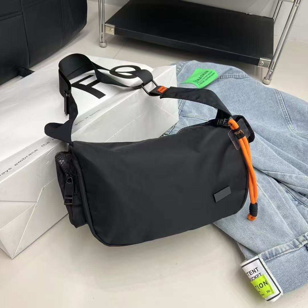 Black waist bag with orange strap on a white surface with jeans and a box in the background Mini utility tote bag 33x22x14 cm with multiple pockets, zip closure, and water-resistant nylon material. Everyday carry tote for men and women, ideal for office, travel, and casual use in India. Alternative to Muji tote, Decathlon utility bag, and Wildcraft crossbody. Features bright orange inner lining and durable adjustable strap.