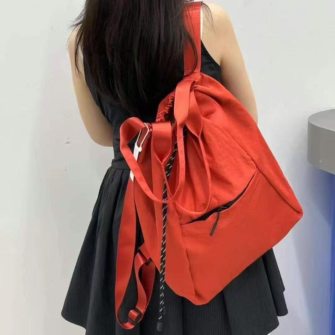Person wearing a red backpack against a white wall,"Stylish khaki drawstring tote bag with multiple compartments and adjustable straps, perfect for daily use, shopping, and travel in India. Features include a secure zippered pocket, spacious main compartment, and comfortable shoulder straps. Ideal for fashion-conscious individuals seeking a versatile and trendy bag."