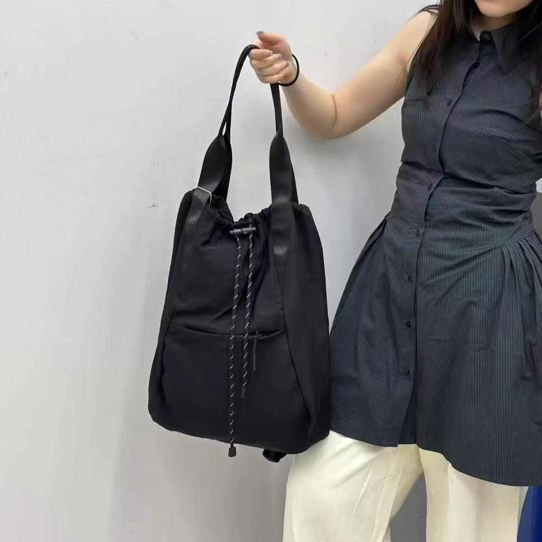 Person holding a black drawstring bag against a plain background,"Stylish khaki drawstring tote bag with multiple compartments and adjustable straps, perfect for daily use, shopping, and travel in India. Features include a secure zippered pocket, spacious main compartment, and comfortable shoulder straps. Ideal for fashion-conscious individuals seeking a versatile and trendy bag."