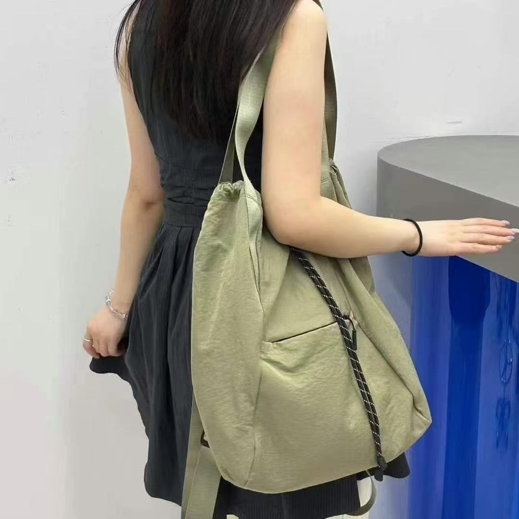 Woman holding a green tote bag against a plain background,"Stylish khaki drawstring tote bag with multiple compartments and adjustable straps, perfect for daily use, shopping, and travel in India. Features include a secure zippered pocket, spacious main compartment, and comfortable shoulder straps. Ideal for fashion-conscious individuals seeking a versatile and trendy bag."