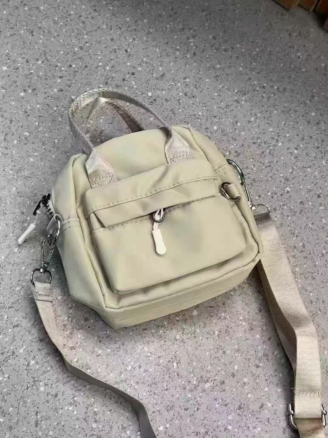Light green backpack with a clear plastic cover on a gray surface,A high-fashion shot of a woman in a black skirt and white shirt, holding a stylish, minimalist brown bag. The image is professionally lit in a studio against a clean white background, with a strong focus on the bag's sleek design and texture. The photo emphasizes a sophisticated and modern aesthetic, perfect for luxury or premium lifestyle brands.