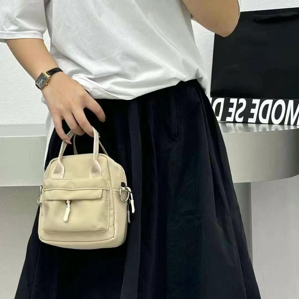 Person holding a beige handbag with a blurred background,A high-fashion shot of a woman in a black skirt and white shirt, holding a stylish, minimalist brown bag. The image is professionally lit in a studio against a clean white background, with a strong focus on the bag's sleek design and texture. The photo emphasizes a sophisticated and modern aesthetic, perfect for luxury or premium lifestyle brands.
