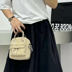 Person holding a beige handbag with a blurred background,A high-fashion shot of a woman in a black skirt and white shirt, holding a stylish, minimalist brown bag. The image is professionally lit in a studio against a clean white background, with a strong focus on the bag's sleek design and texture. The photo emphasizes a sophisticated and modern aesthetic, perfect for luxury or premium lifestyle brands.
