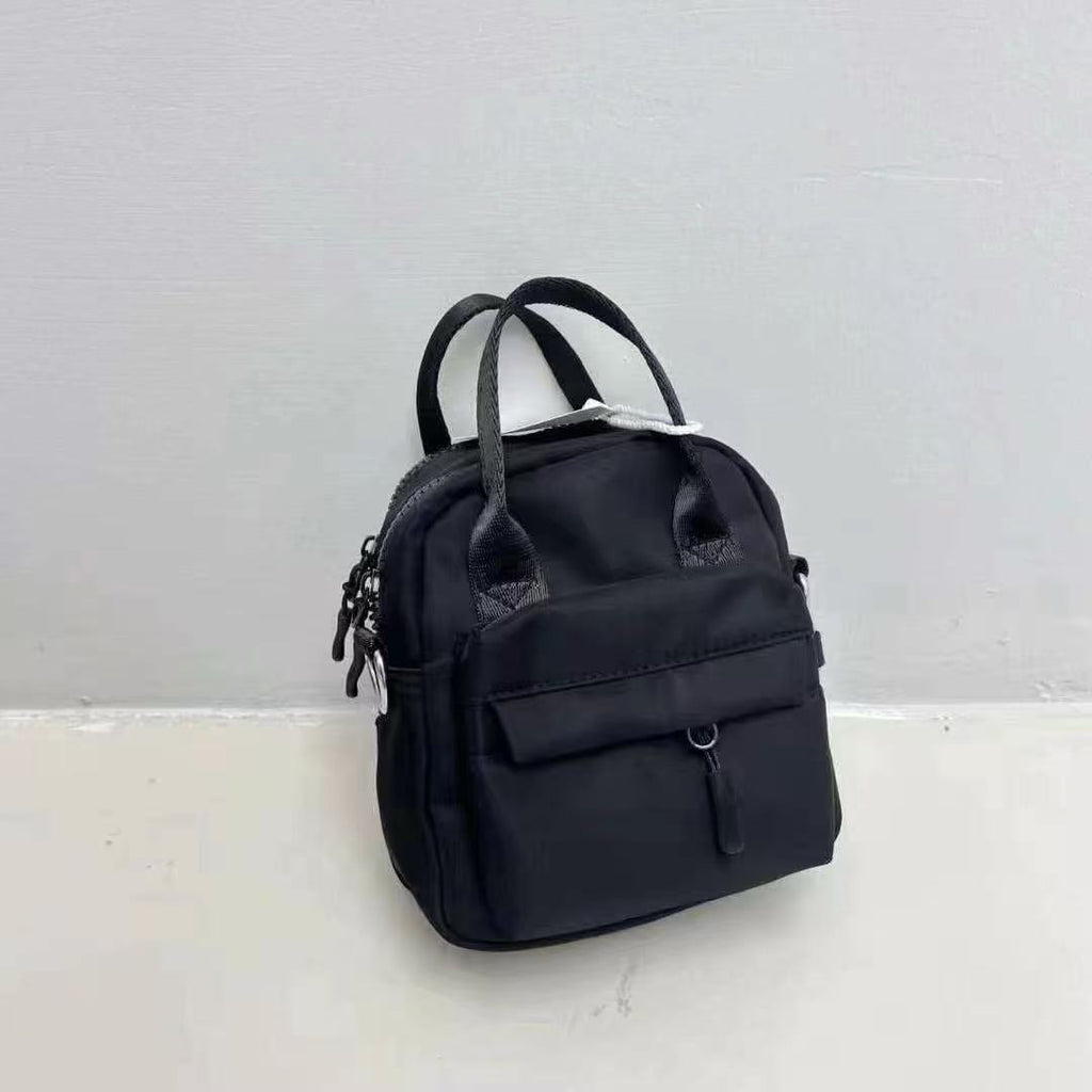 Black backpack on a light gray background,A high-fashion shot of a woman in a black skirt and white shirt, holding a stylish, minimalist brown bag. The image is professionally lit in a studio against a clean white background, with a strong focus on the bag's sleek design and texture. The photo emphasizes a sophisticated and modern aesthetic, perfect for luxury or premium lifestyle brands.