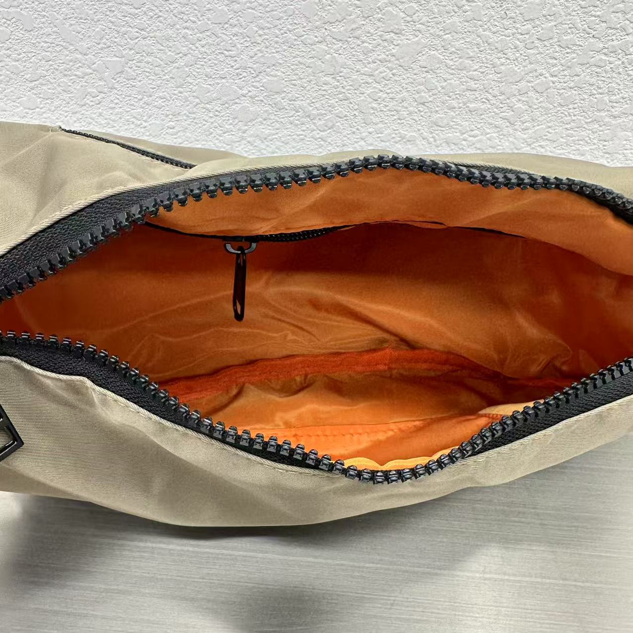 Open beige bag with orange interior on a textured surface,Mini utility tote bag 33x22x14 cm with multiple pockets, zip closure, and water-resistant nylon material. Everyday carry tote for men and women, ideal for office, travel, and casual use in India. Alternative to Muji tote, Decathlon utility bag, and Wildcraft crossbody. Features bright orange inner lining and durable adjustable strap.