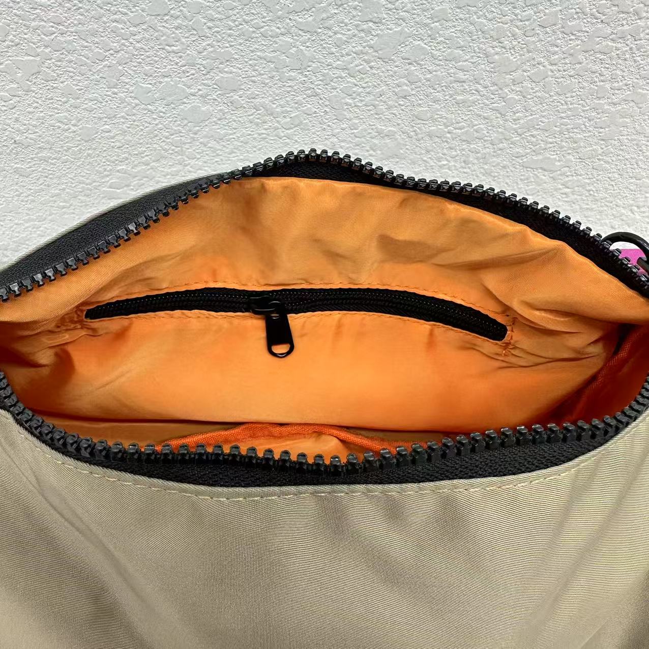 Open beige bag with orange interior and black zipper on a light gray background,Mini utility tote bag 33x22x14 cm with multiple pockets, zip closure, and water-resistant nylon material. Everyday carry tote for men and women, ideal for office, travel, and casual use in India. Alternative to Muji tote, Decathlon utility bag, and Wildcraft crossbody. Features bright orange inner lining and durable adjustable strap.