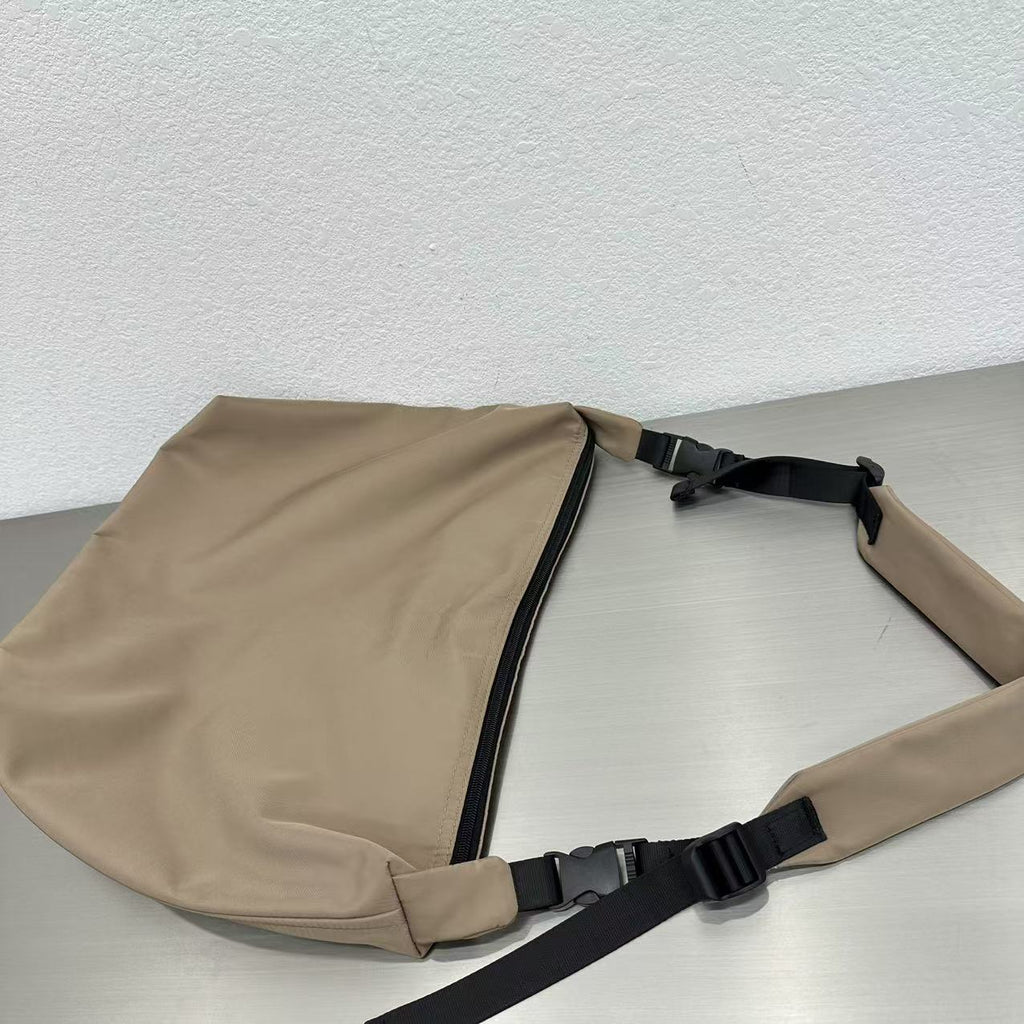 Beige sling bag with black straps on a light gray surface,Convertible nylon tote bag with detachable crossbody strap, zippered front pocket, and main compartment. Available in olive green, black, and beige.