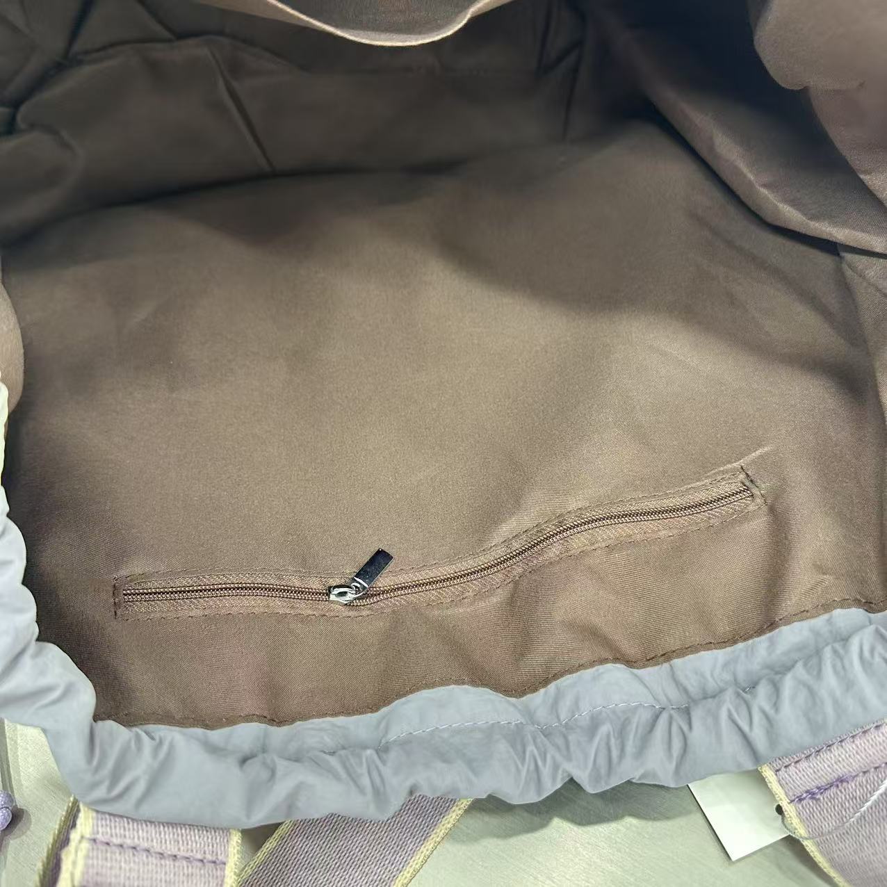 Close-up of a brown fabric with a zipper on a textured surface,A versatile and stylish tote bag for women, perfect for the Indian market, shot from a side angle showing the product in use. The bag is made from a durable, high-quality fabric and features a casual, comfortable design with shoulder straps. This fashion accessory is ideal for a daily commute, college, or casual outings. It's a must-have for those seeking a practical yet trendy handbag in India.