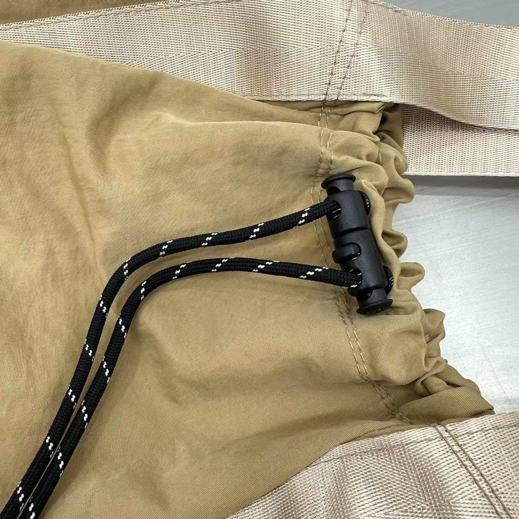 Close-up of beige fabric with a black cord and buckle,"Stylish khaki drawstring tote bag with multiple compartments and adjustable straps, perfect for daily use, shopping, and travel in India. Features include a secure zippered pocket, spacious main compartment, and comfortable shoulder straps. Ideal for fashion-conscious individuals seeking a versatile and trendy bag."