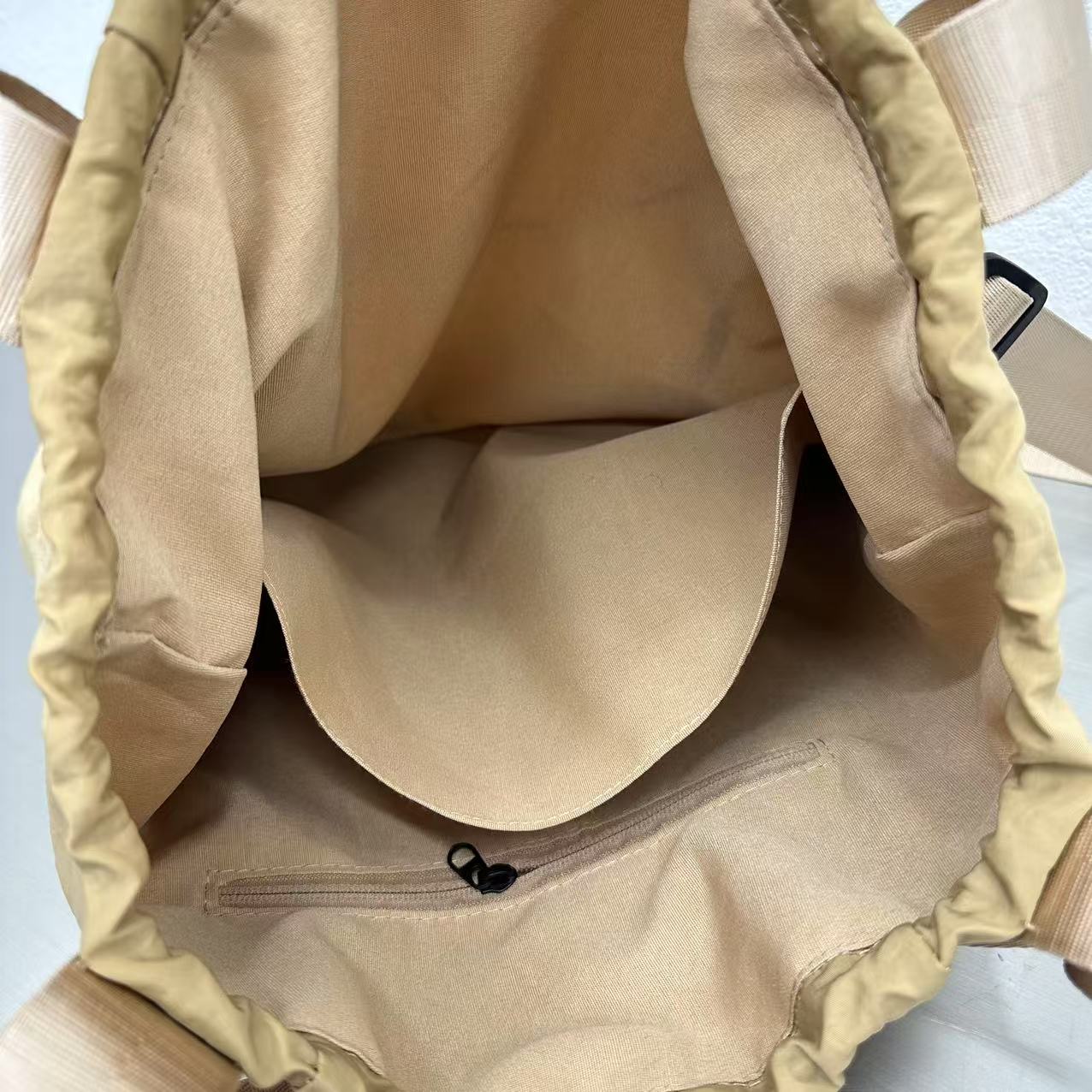 Close-up of a beige bag with a zipper on a light blue background,"Stylish khaki drawstring tote bag with multiple compartments and adjustable straps, perfect for daily use, shopping, and travel in India. Features include a secure zippered pocket, spacious main compartment, and comfortable shoulder straps. Ideal for fashion-conscious individuals seeking a versatile and trendy bag."