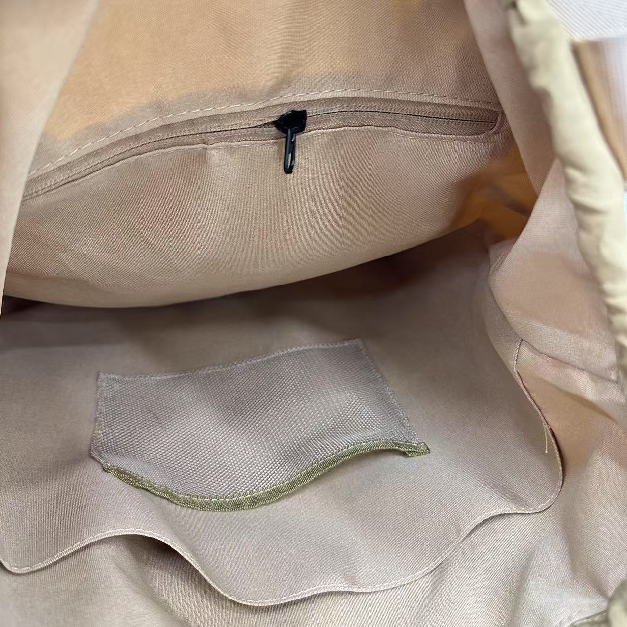 Close-up of beige fabric with a zipper and mesh pocket"Stylish khaki drawstring tote bag with multiple compartments and adjustable straps, perfect for daily use, shopping, and travel in India. Features include a secure zippered pocket, spacious main compartment, and comfortable shoulder straps. Ideal for fashion-conscious individuals seeking a versatile and trendy bag."
