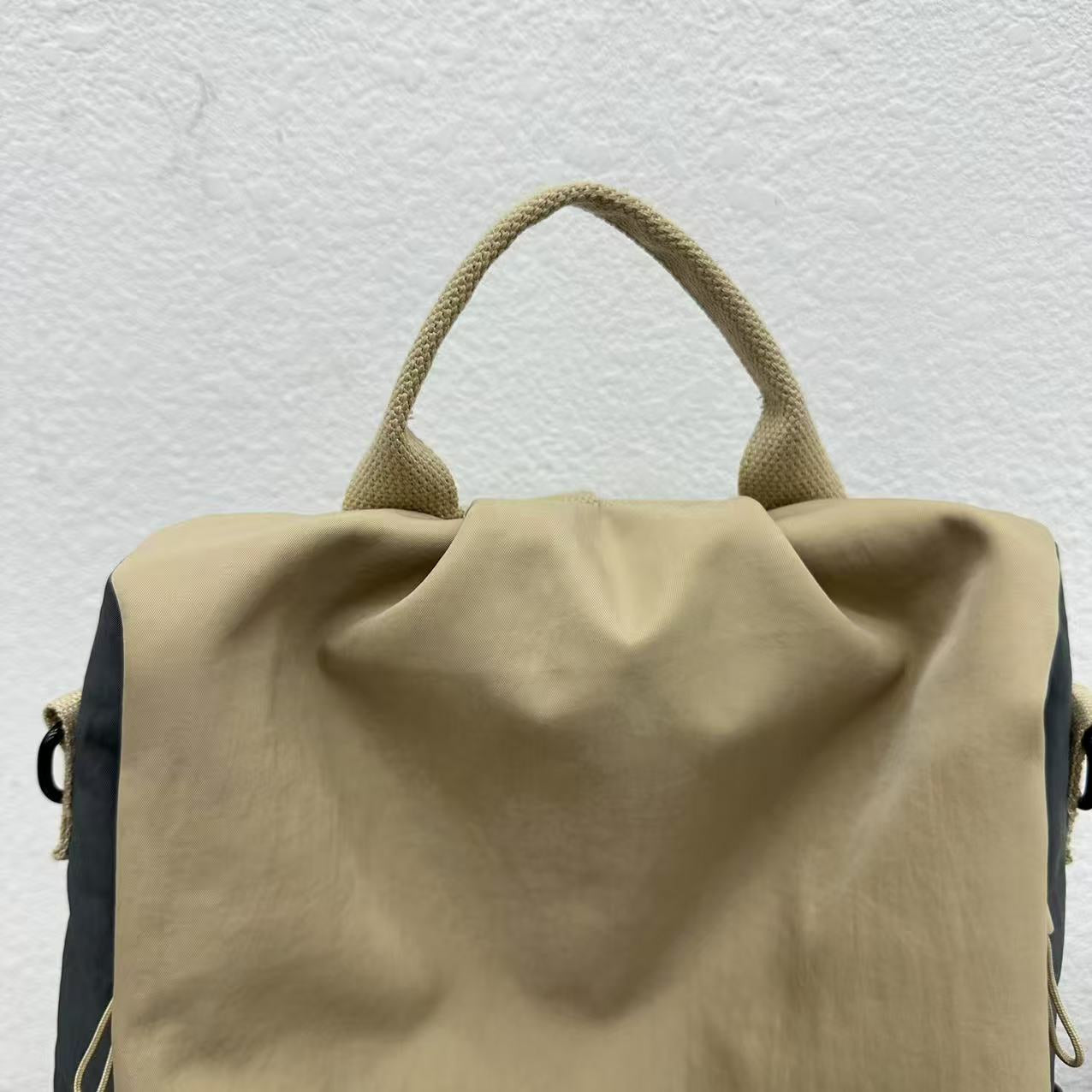 Beige backpack with a textured handle on a light gray background,Stylish travel backpack, durable everyday bag, versatile shoulder tote, convertible backpack purse, waterproof utility bag, modern casual rucksack, ergonomic daypack, trendy laptop bag, multi-functional women's backpack, secure anti-theft design, spacious college bag, fashion-forward accessory, urban commuter pack, comfortable carry-all, premium quality satchel, practical work bag, chic student backpack, easy-access travel essential, organized