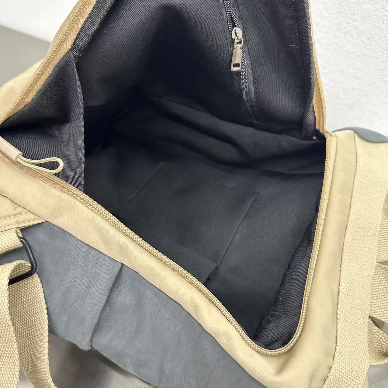 Open beige and black duffel bag showing interior.Stylish travel backpack, durable everyday bag, versatile shoulder tote, convertible backpack purse, waterproof utility bag, modern casual rucksack, ergonomic daypack, trendy laptop bag, multi-functional women's backpack, secure anti-theft design, spacious college bag, fashion-forward accessory, urban commuter pack, comfortable carry-all, premium quality satchel, practical work bag, chic student backpack, easy-access travel essential, organized personal item, 