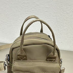 Khaki backpack with multiple straps on a textured light gray background,A high-fashion shot of a woman in a black skirt and white shirt, holding a stylish, minimalist brown bag. The image is professionally lit in a studio against a clean white background, with a strong focus on the bag's sleek design and texture. The photo emphasizes a sophisticated and modern aesthetic, perfect for luxury or premium lifestyle brands.