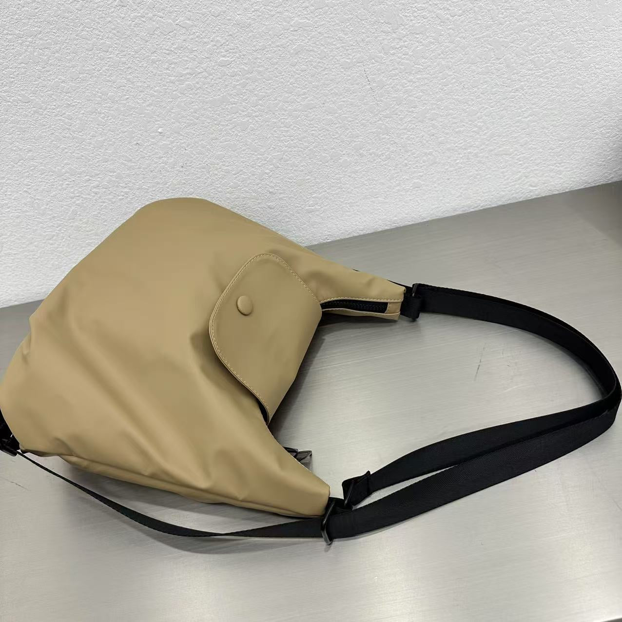 Beige shoulder bag with a black strap on a light gray surface,laptop tote bag for women, tote bag for office use, college tote bag with zipper, and stylish bags for girls. You can also target users with specific needs by using long-tail phrases like vegan leather tote bag or tote bag for daily use in India. To understand the market better, keep an eye on competitors such as Lavie, Baggit, and Caprese, all of which are major players in the Indian handbag space, along with brands like Zouk and Hidesign that c