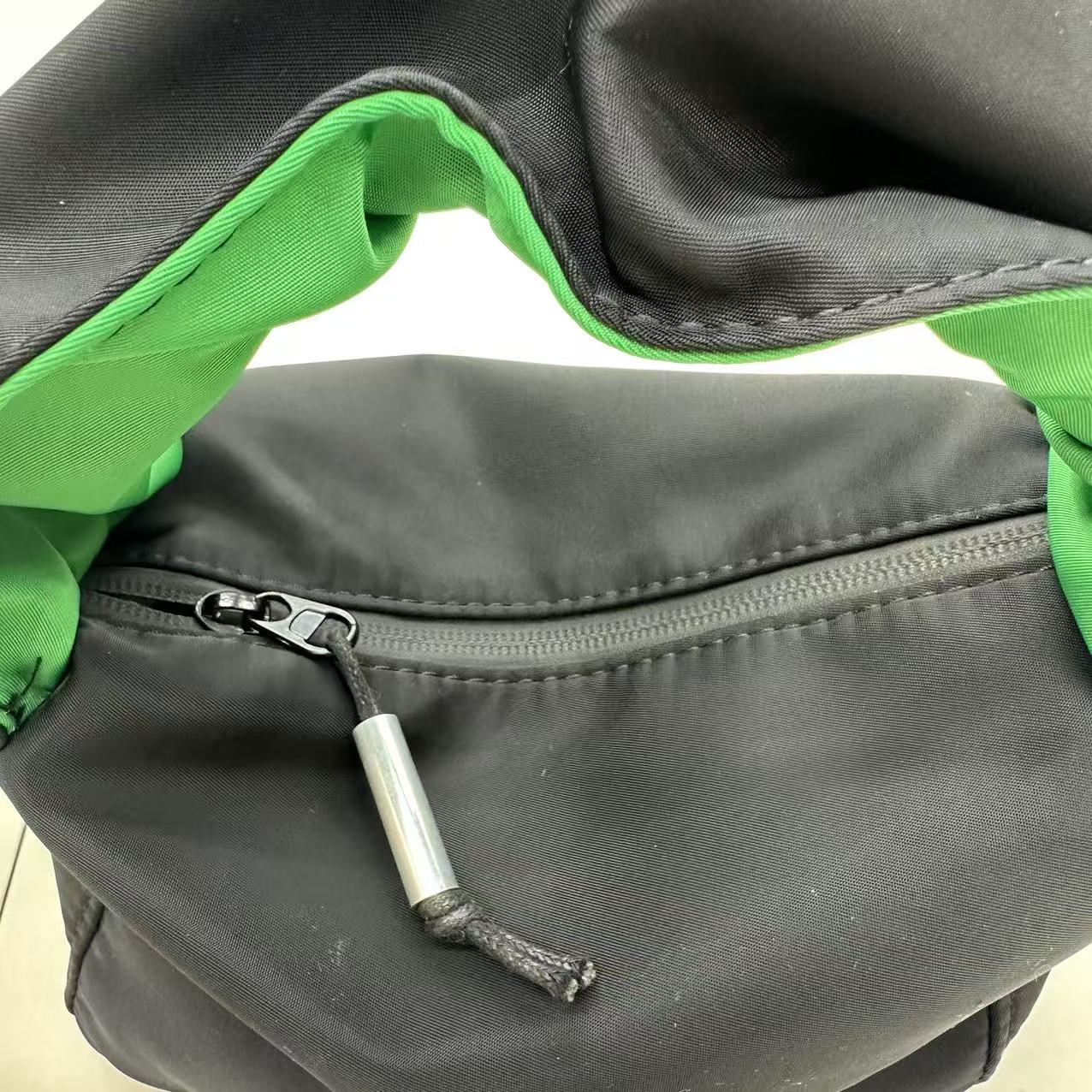 Close-up of a black and green bag with a zipper"Black waterproof polyester mini tote bag with stylish green lining, lightweight and durable design, adjustable crossbody strap and spacious compartments for wallet, phone, cosmetics and daily essentials. Perfect handbag for women in India for office, college, travel, shopping, and everyday use. Premium quality ladies tote bag available online at best price in India, versatile small carry bag for students, professionals, and travelers."