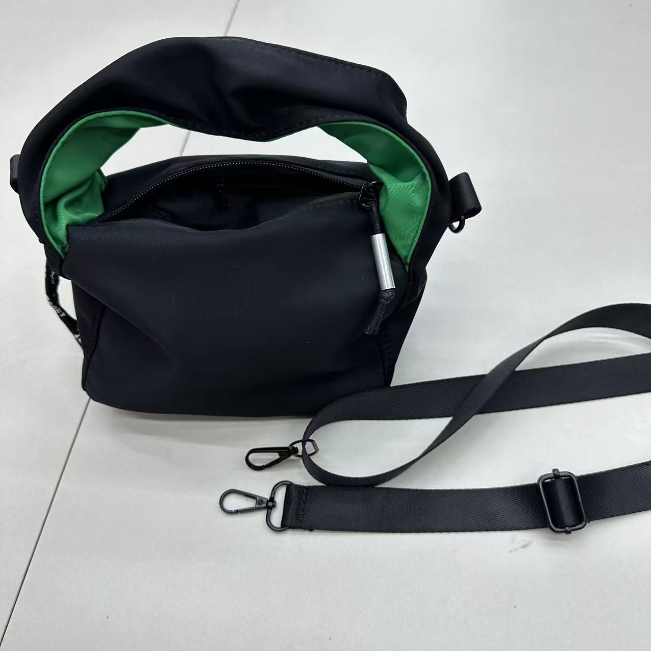 Black bag with green interior on a light gray surface';"Black waterproof polyester mini tote bag with stylish green lining, lightweight and durable design, adjustable crossbody strap and spacious compartments for wallet, phone, cosmetics and daily essentials. Perfect handbag for women in India for office, college, travel, shopping, and everyday use. Premium quality ladies tote bag available online at best price in India, versatile small carry bag for students, professionals, and travelers."