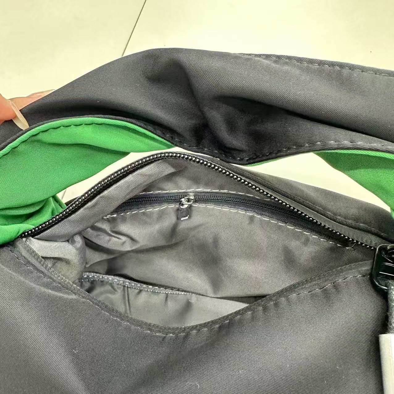Gray bag with a zipper, showing green interior.."Black waterproof polyester mini tote bag with stylish green lining, lightweight and durable design, adjustable crossbody strap and spacious compartments for wallet, phone, cosmetics and daily essentials. Perfect handbag for women in India for office, college, travel, shopping, and everyday use. Premium quality ladies tote bag available online at best price in India, versatile small carry bag for students, professionals, and travelers."