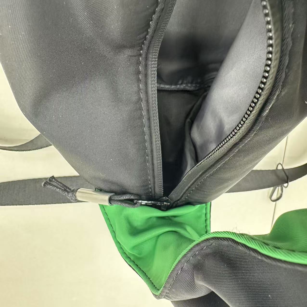 Close-up of a gray and green bag with a zipper."Black waterproof polyester mini tote bag with stylish green lining, lightweight and durable design, adjustable crossbody strap and spacious compartments for wallet, phone, cosmetics and daily essentials. Perfect handbag for women in India for office, college, travel, shopping, and everyday use. Premium quality ladies tote bag available online at best price in India, versatile small carry bag for students, professionals, and travelers."