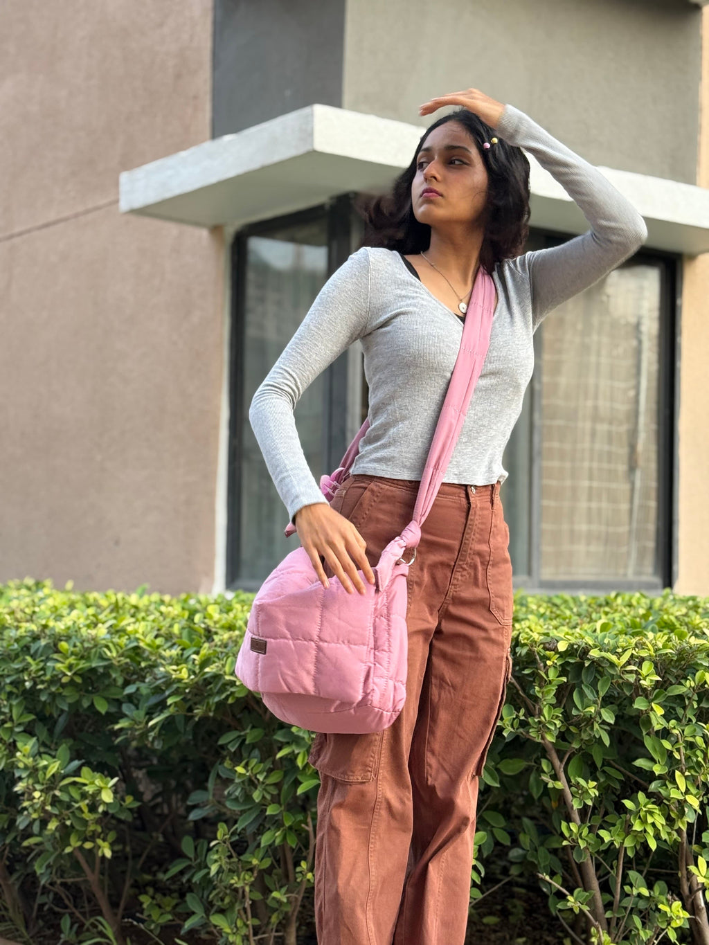 Woman holding a pink bag outdoors with a building in the background Quilted shoulder bag with a padded design, knotted strap detail, and soft structured silhouette – lightweight, functional, and perfect for daily use or casual outings. Compact yet spacious, ideal for carrying essentials in style. A statement accessory from Tales of Totes, offering cozy fashion-forward appeal for Indian shoppers.