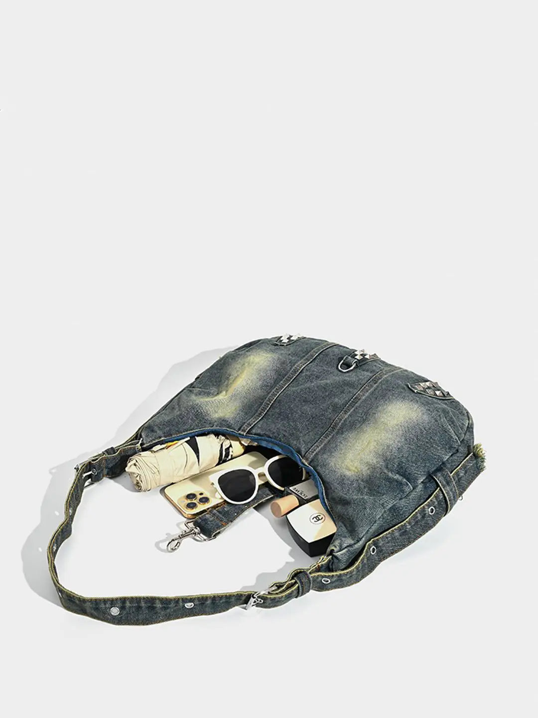 Blue denim handbag with sunglasses and money on a white background