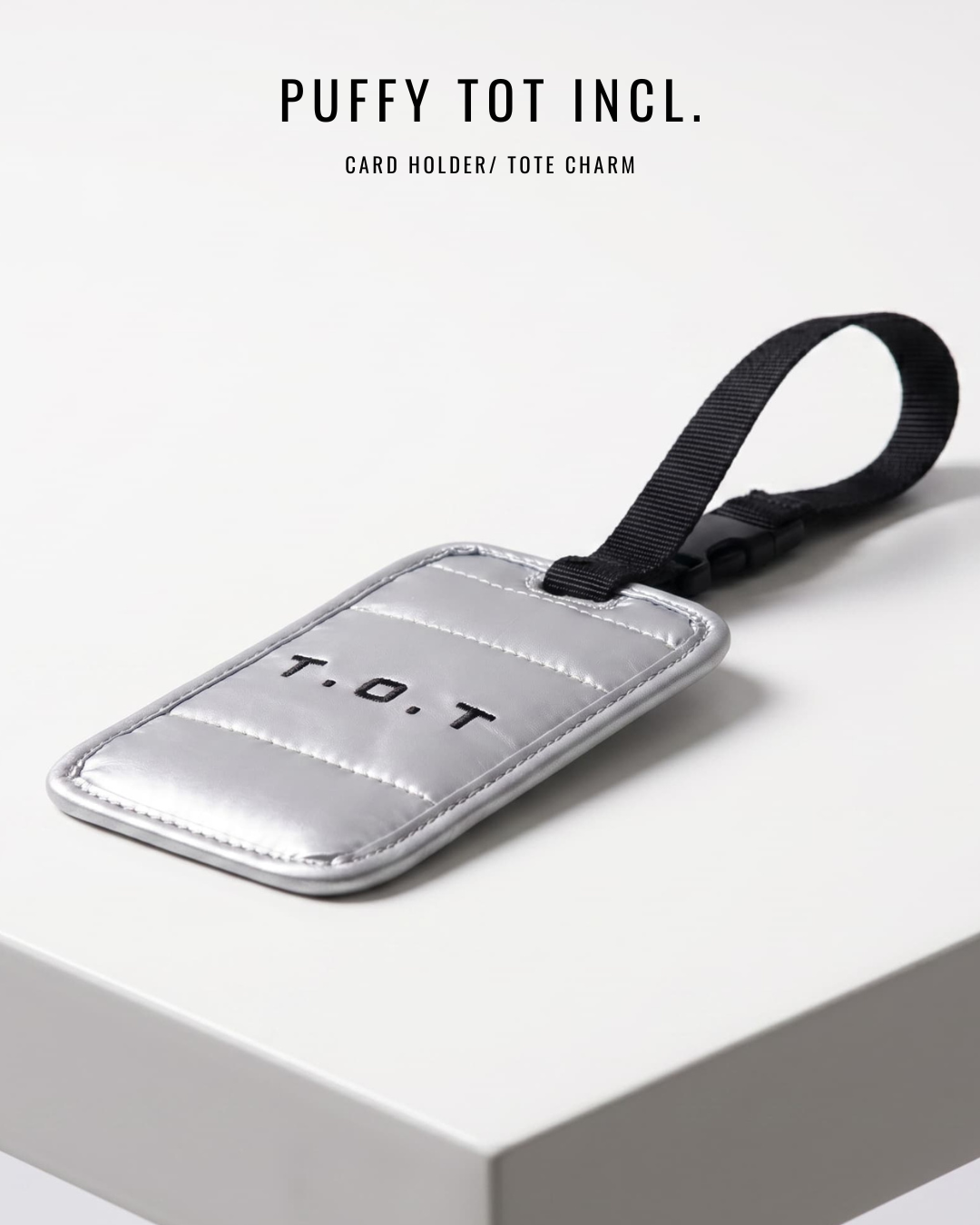 Silver puffy card holder with black strap on a white background