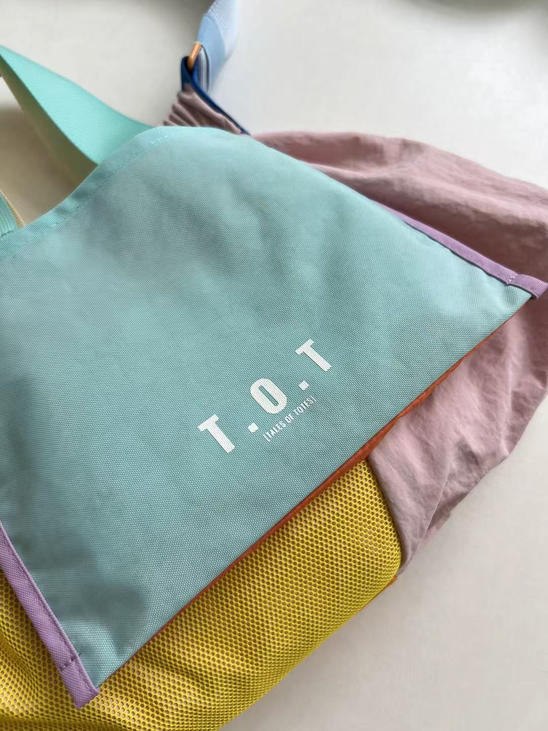 Trendy multi-color casual college tote bag with mesh detailing and adjustable straps.