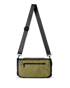 Green crossbody bag with black strap on a white background