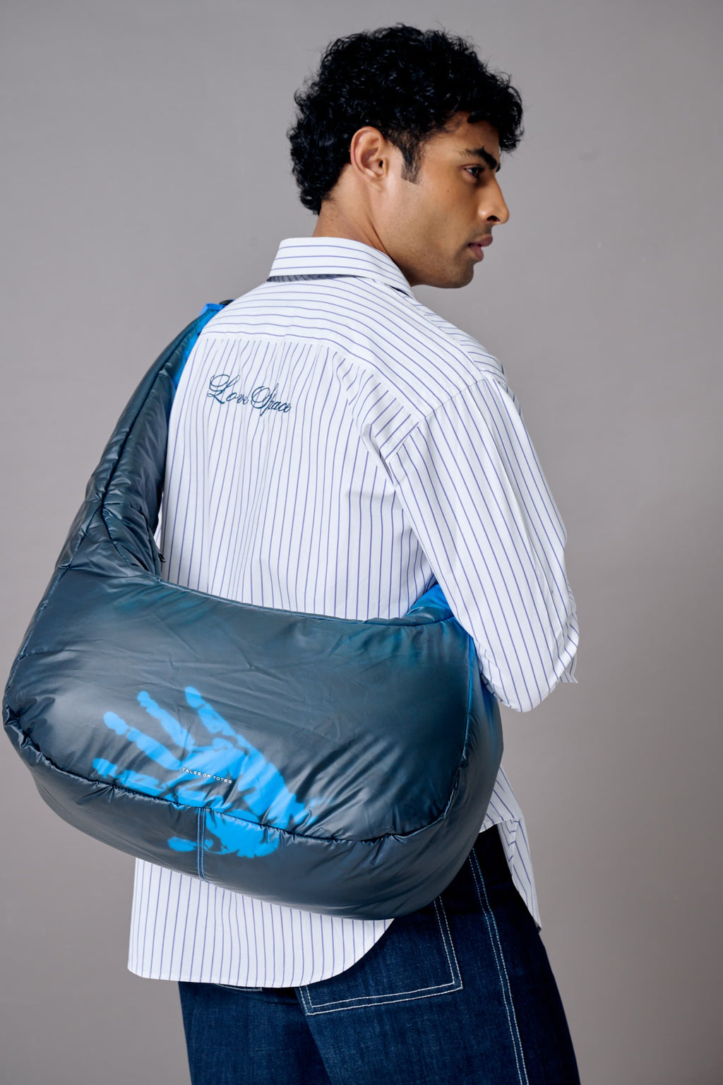 Person holding a gray sleeping bag with blue handprints on a gray background