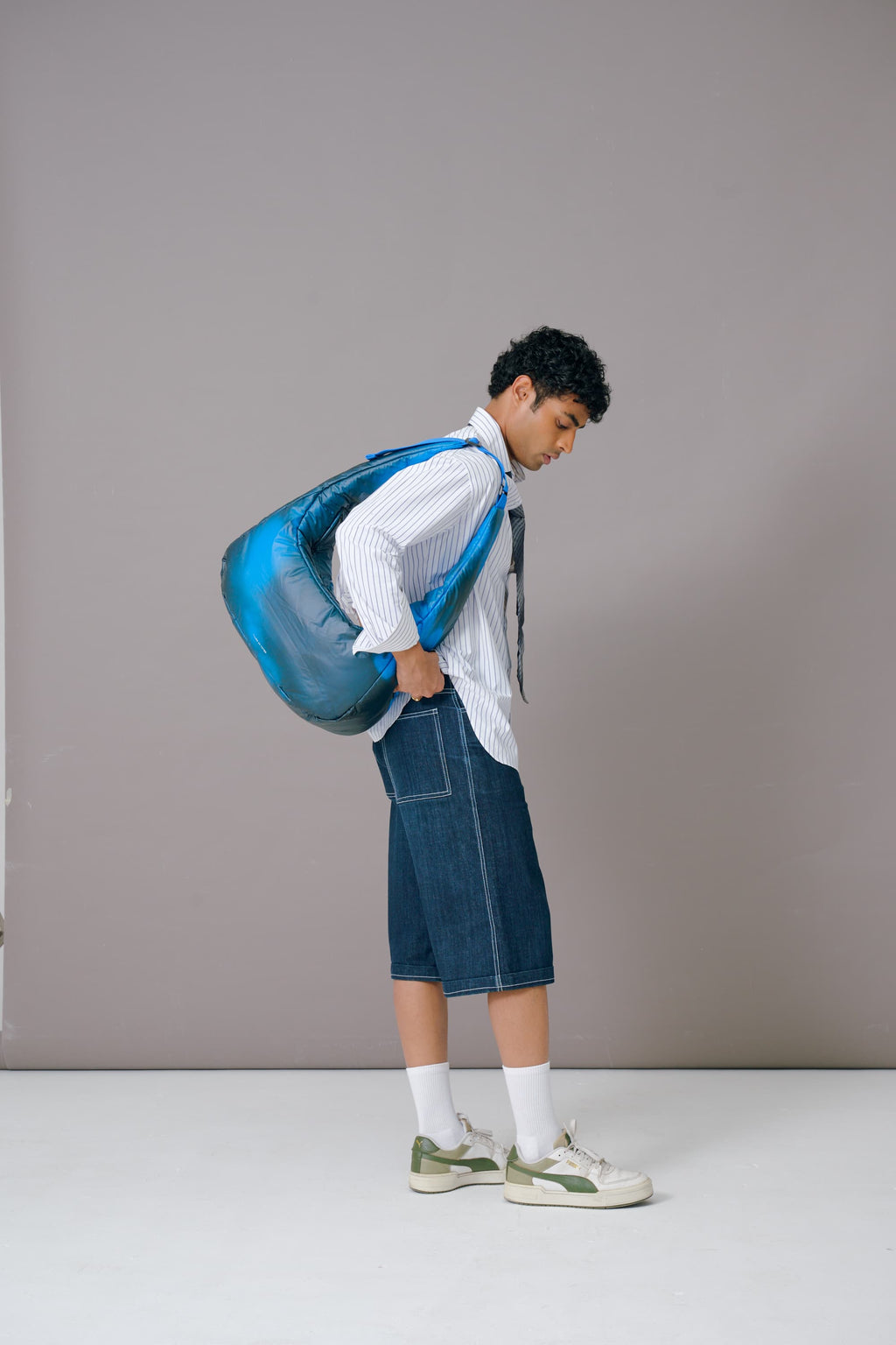 Person holding a large blue bag against a plain background