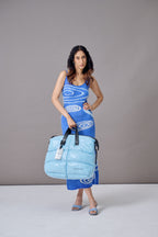 Woman holding a blue bag against a gray background