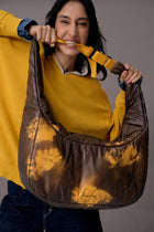 Woman holding a large brown bag with a yellow pattern against a gray background