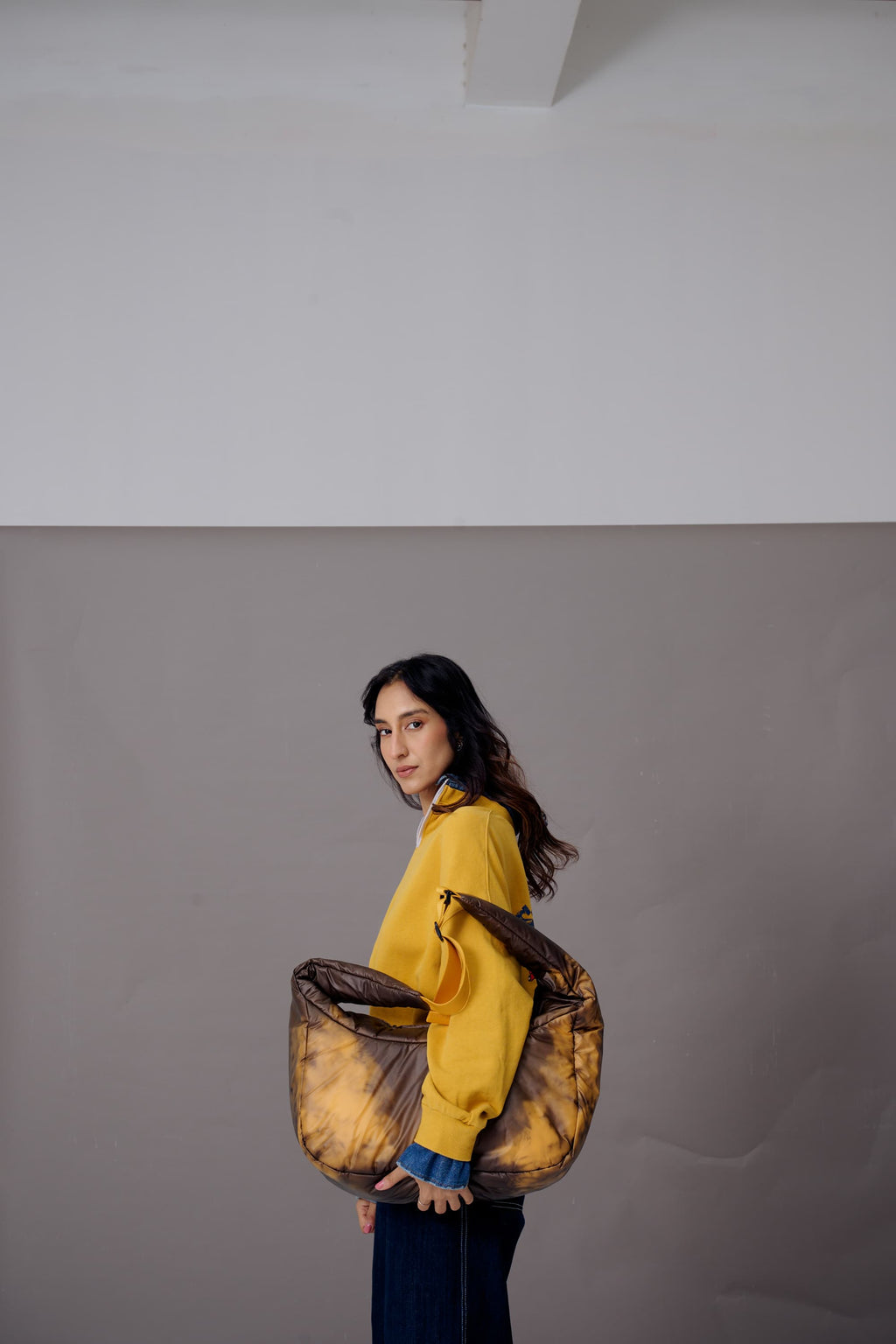 Woman holding a large brown bag against a gray background