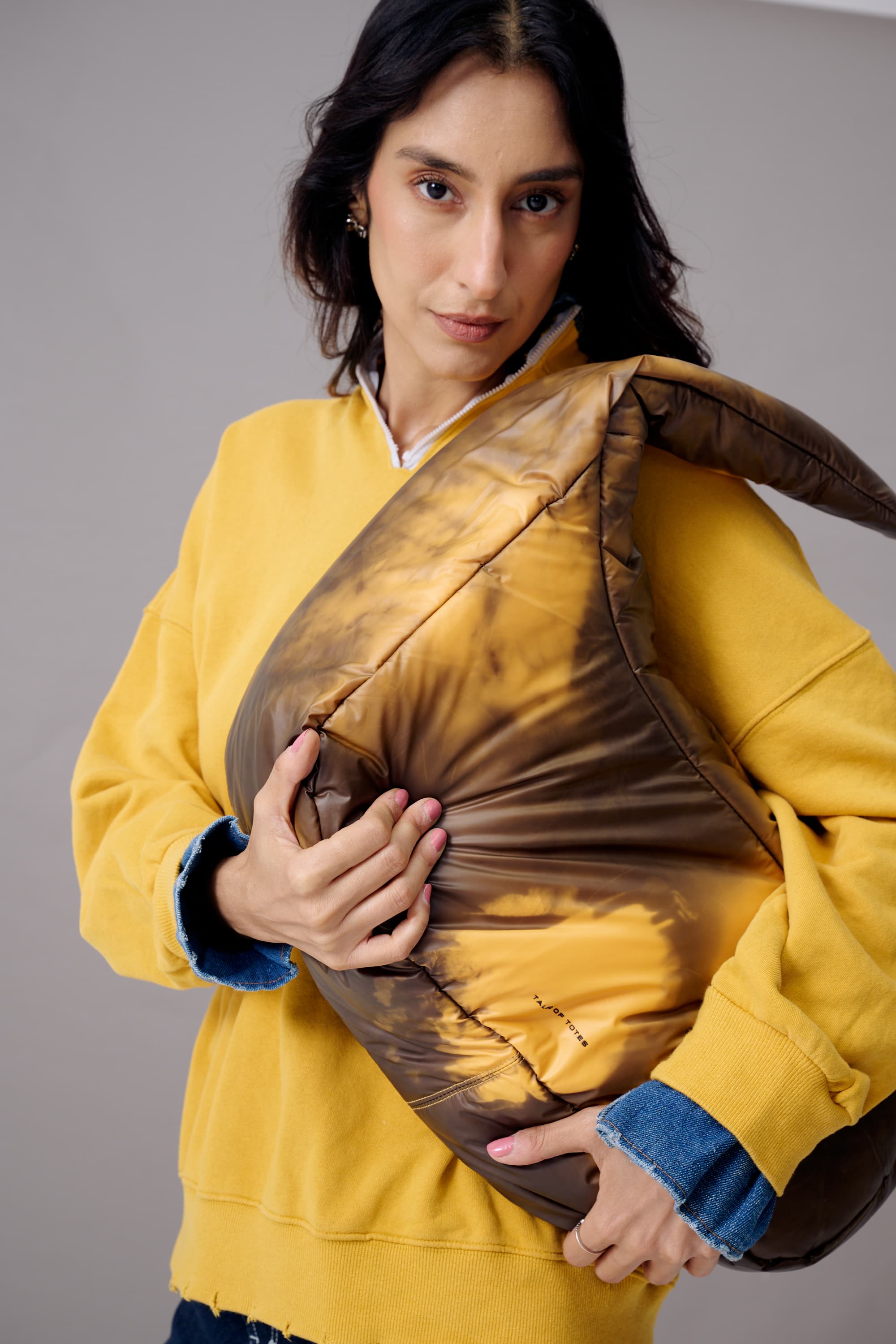 Woman holding a brown cushion against a gray background