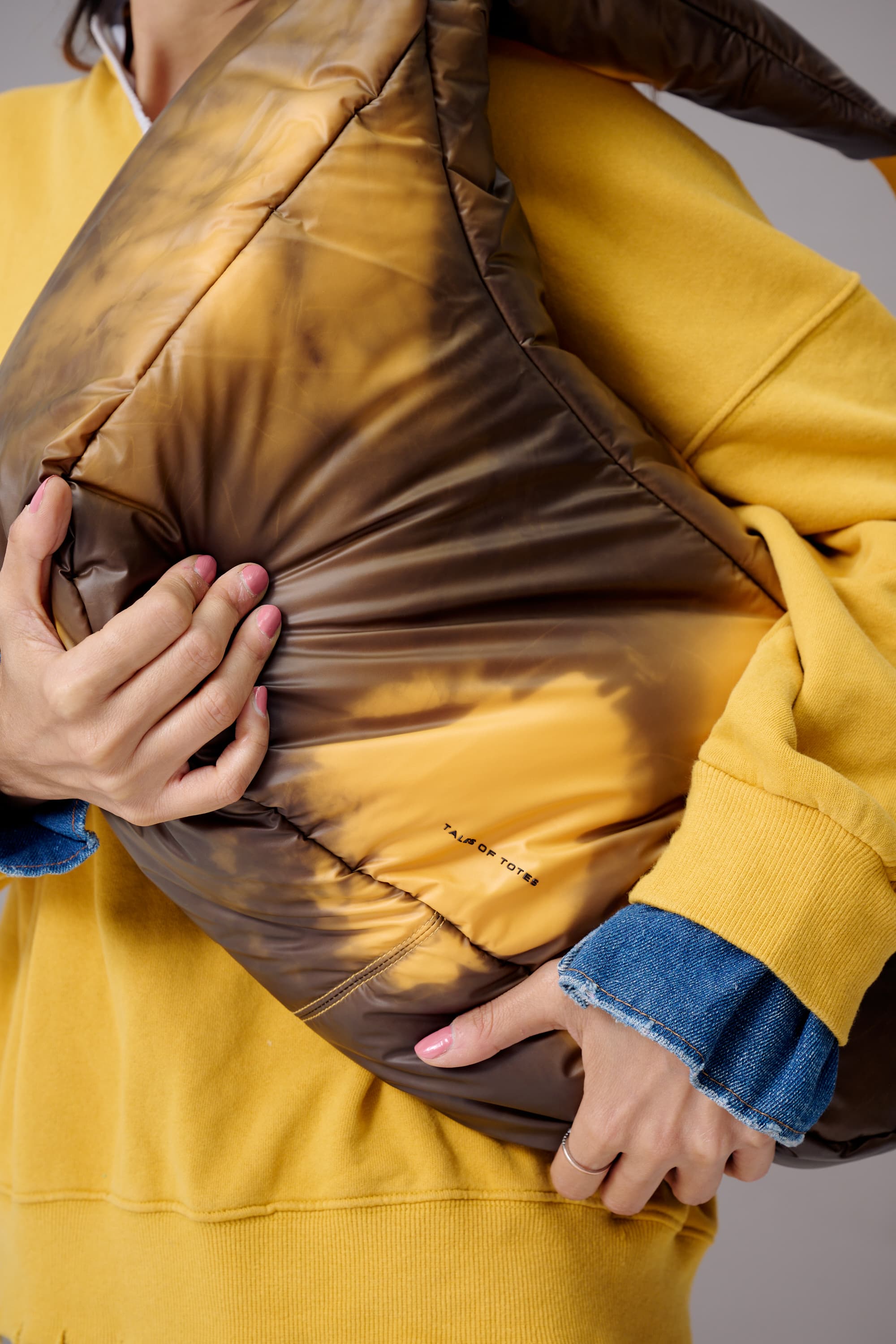 Person wearing a yellow jacket with a brown puffer insert, holding the jacket open.