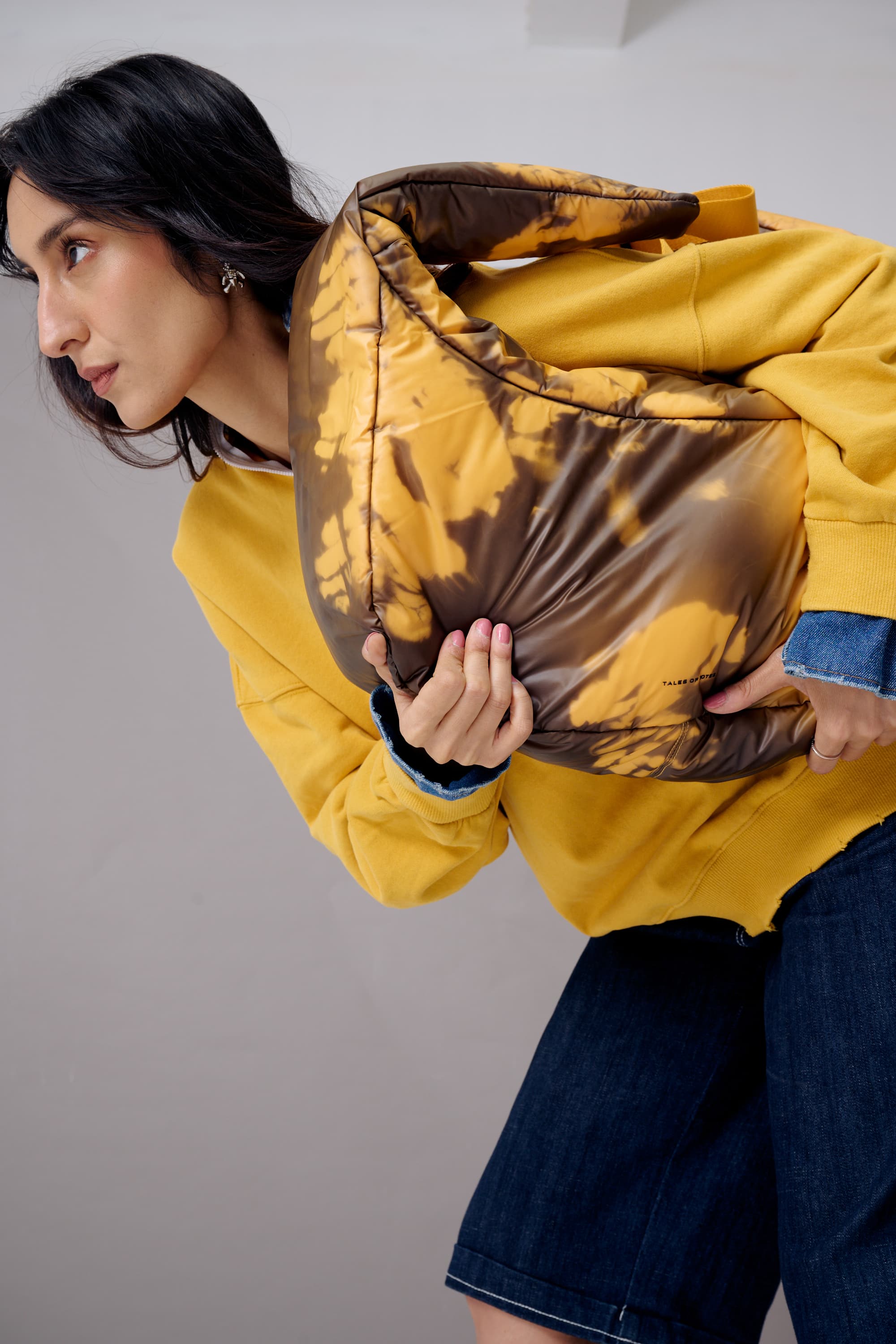 Woman wearing a yellow jacket with a tie-dye pattern, holding it open to show the design.
