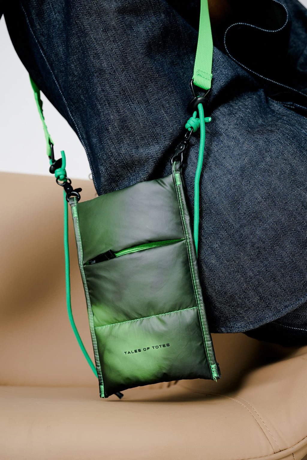 Green crossbody bag with a strap over shoulder on a neutral background