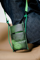 Green crossbody bag with a strap over shoulder on a neutral background