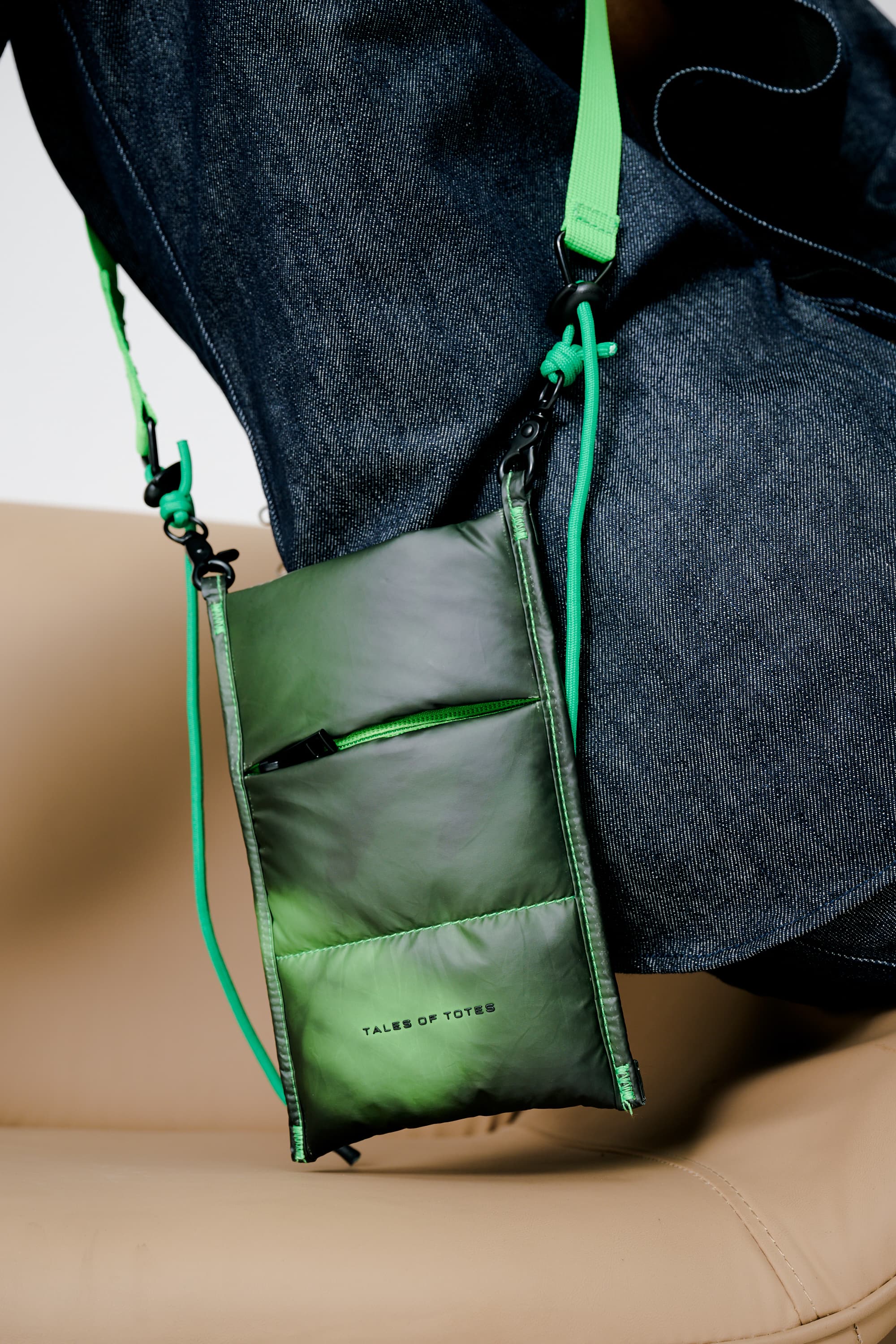 Green crossbody bag with a strap over shoulder on a neutral background