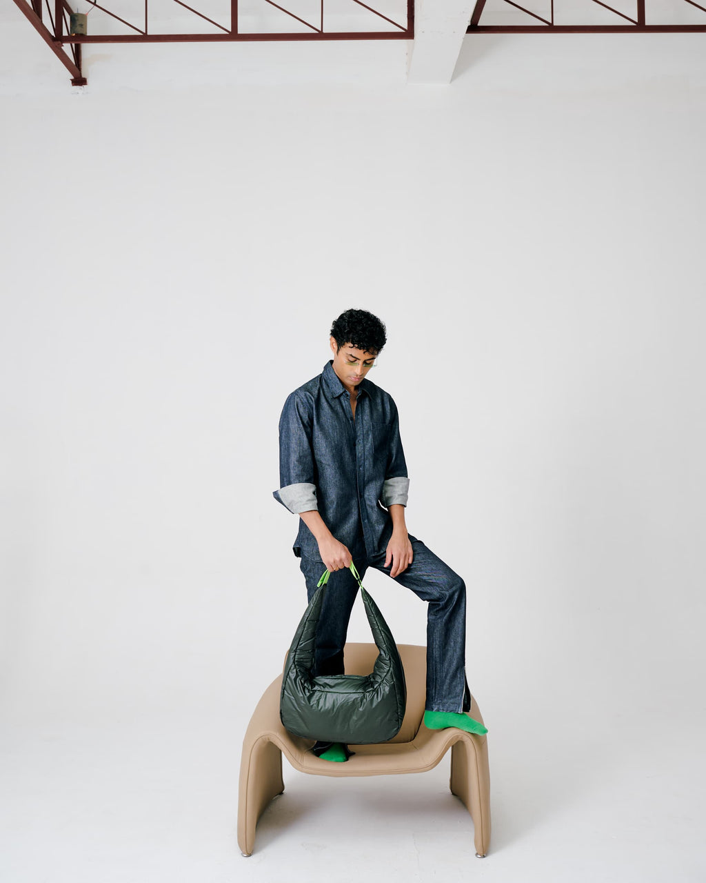 Person sitting on a chair holding a green bag against a white background