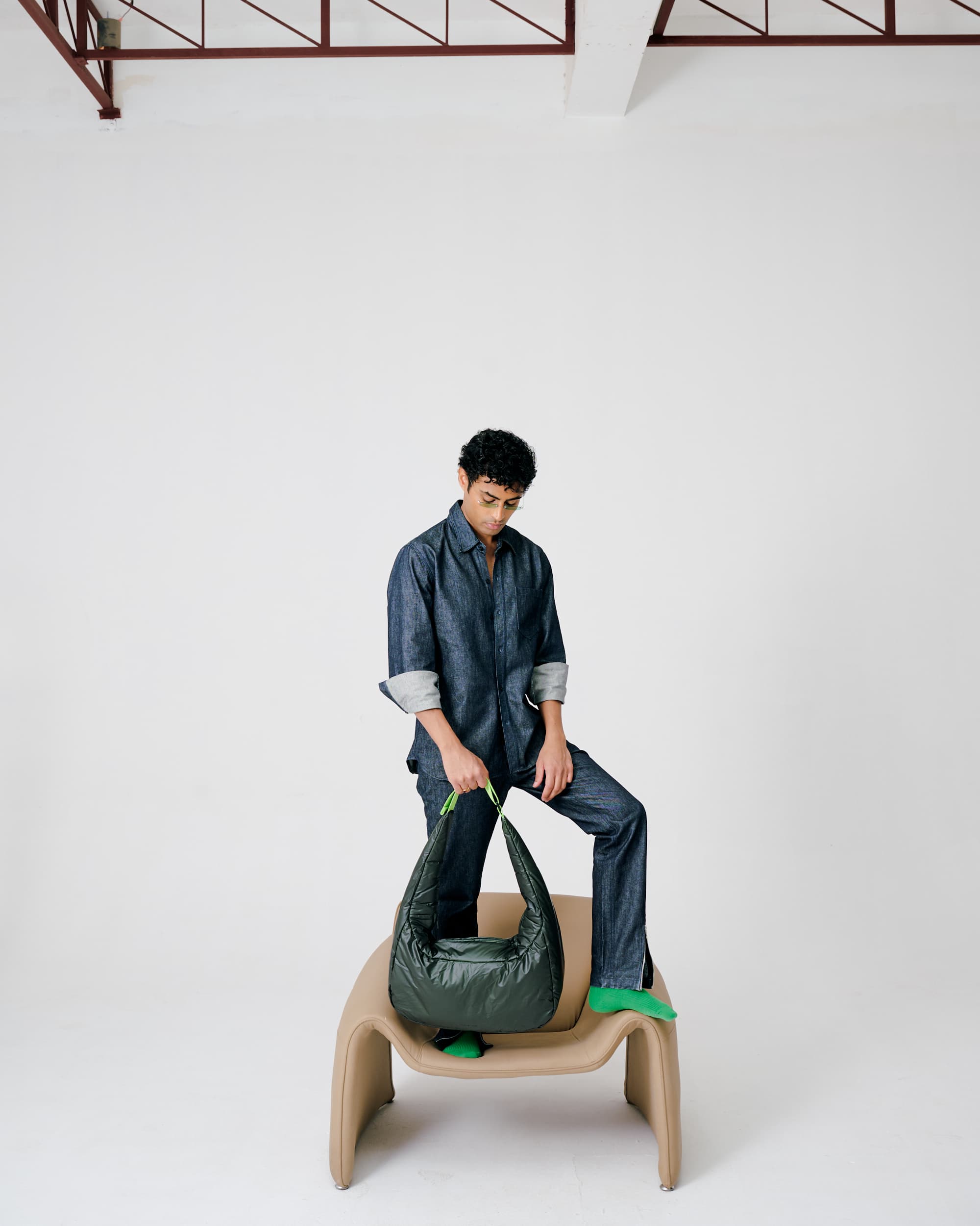 Person sitting on a chair holding a green bag against a white background