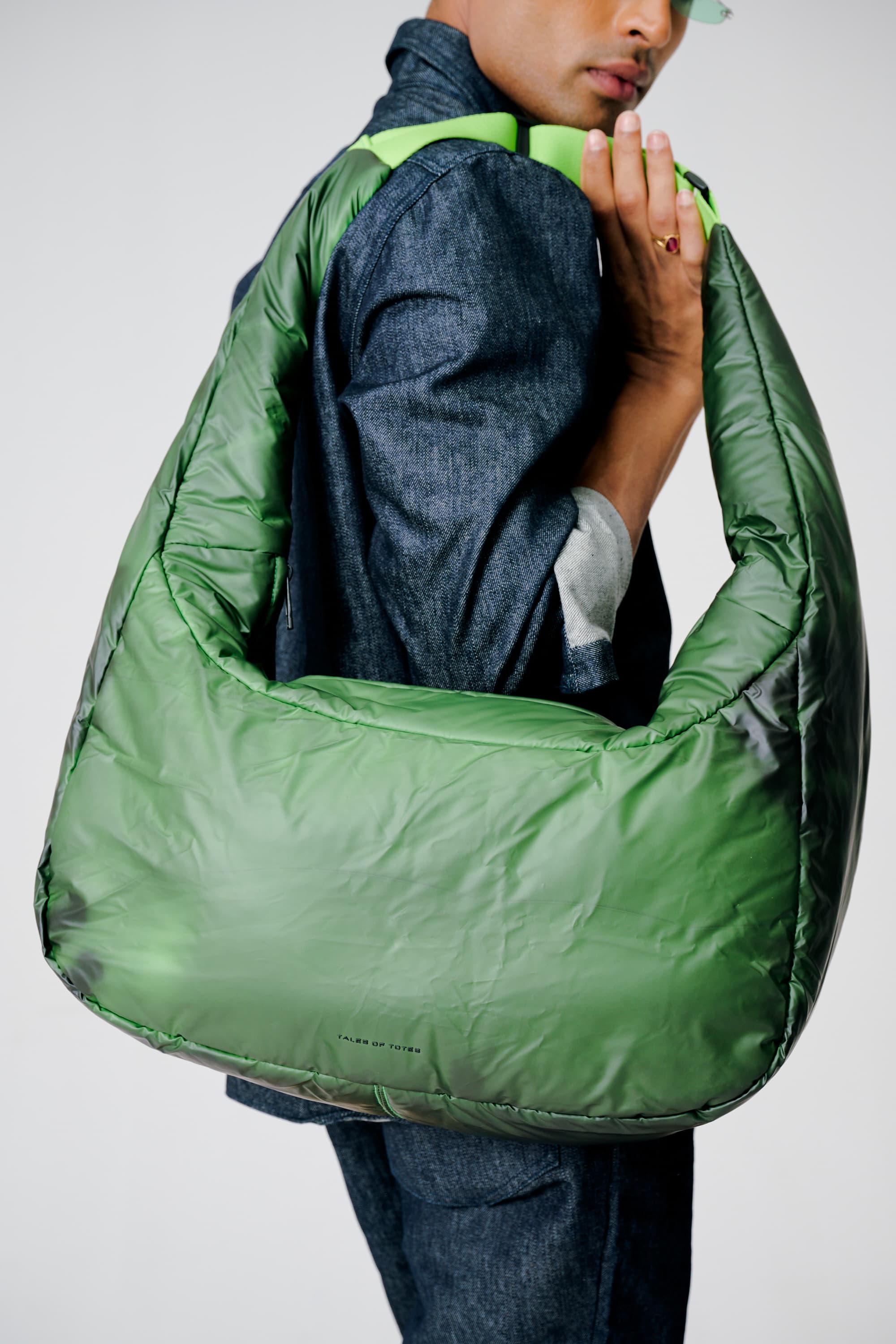 Person holding a large green bag against a plain background
