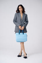 Woman holding a light blue handbag against a white background
