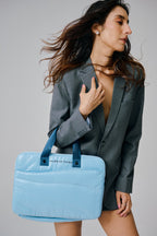 Woman holding a light blue tote bag against a plain background