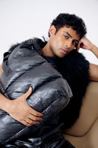 Man holding a large black puffer bag against a neutral background