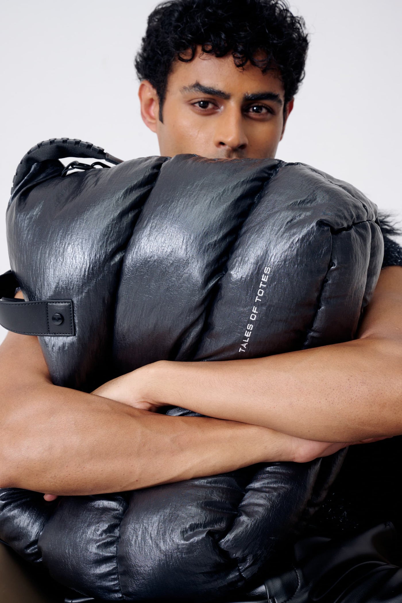 Person holding a large black bag with 'Tote' branding on a white background